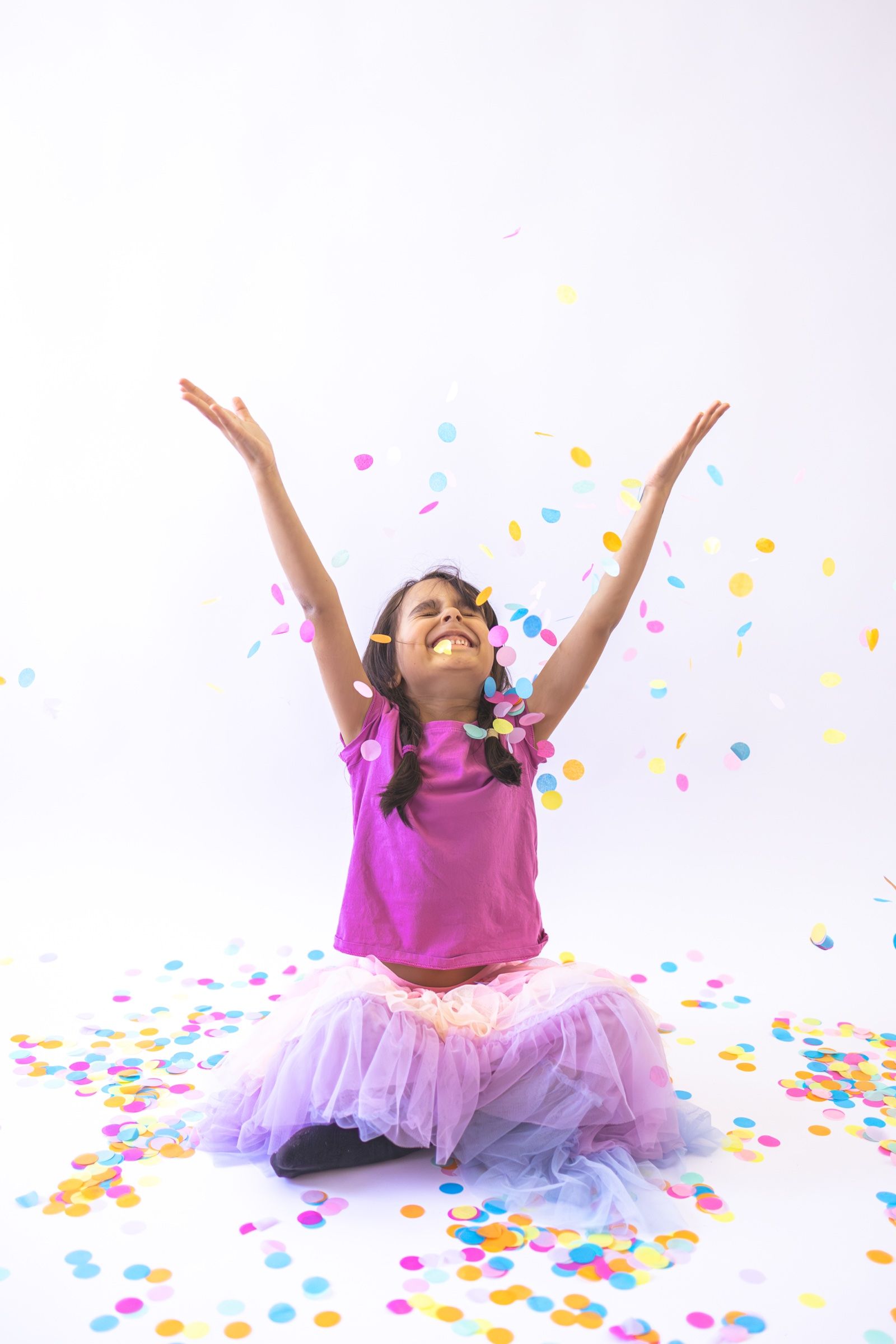 Girl in a pink top throwing colorful confetti into the air
