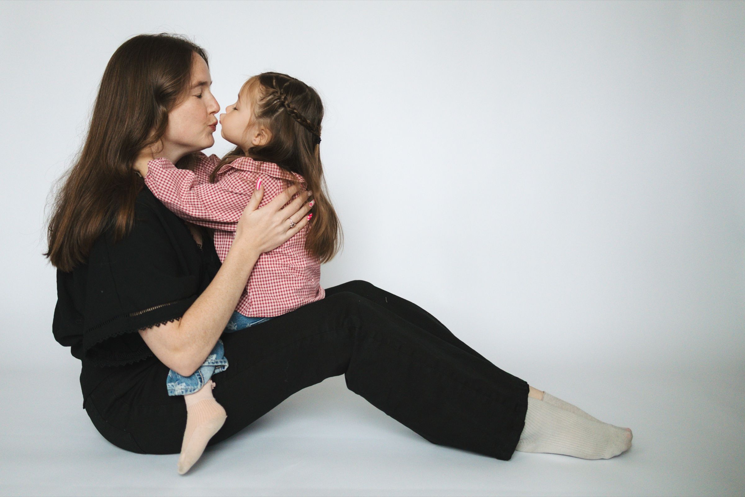 Mother and young daughter sharing a tender kiss on the floor