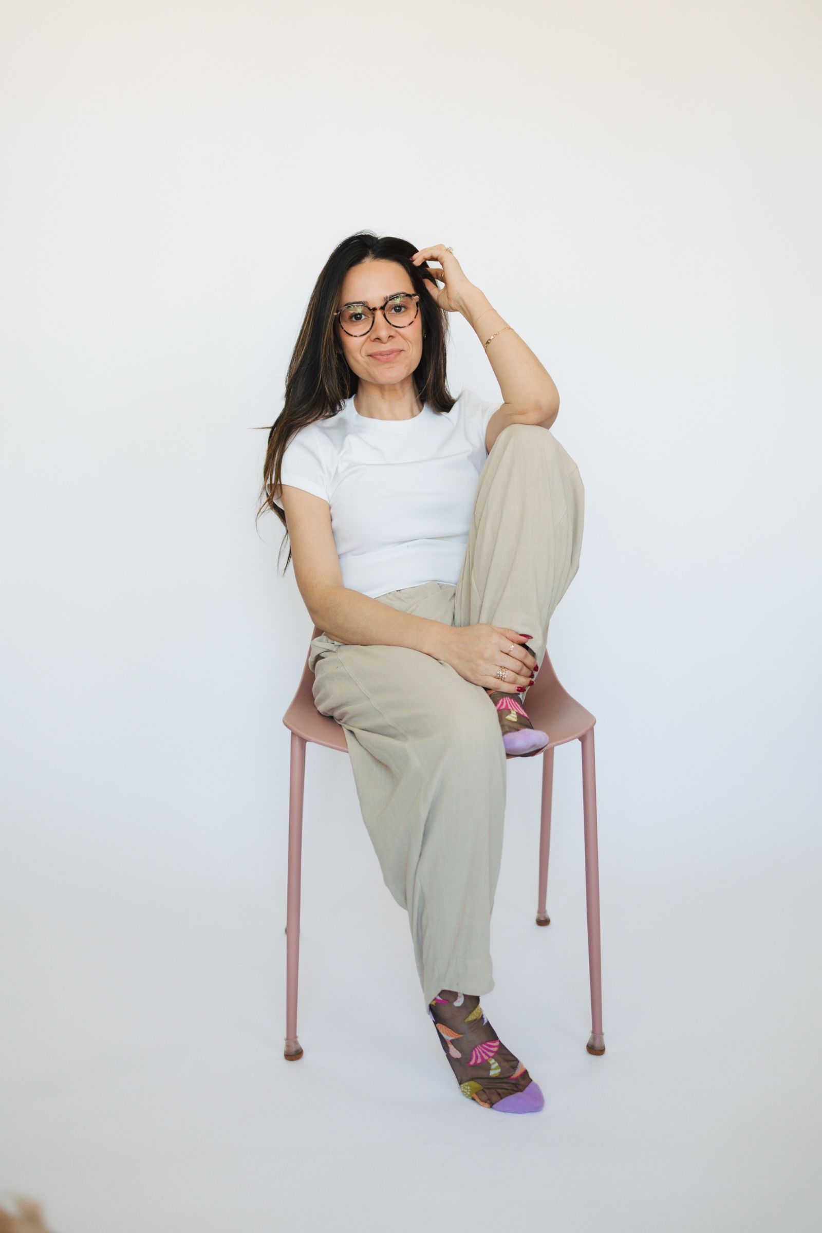 Woman with glasses seated on a pink chair, casual portrait