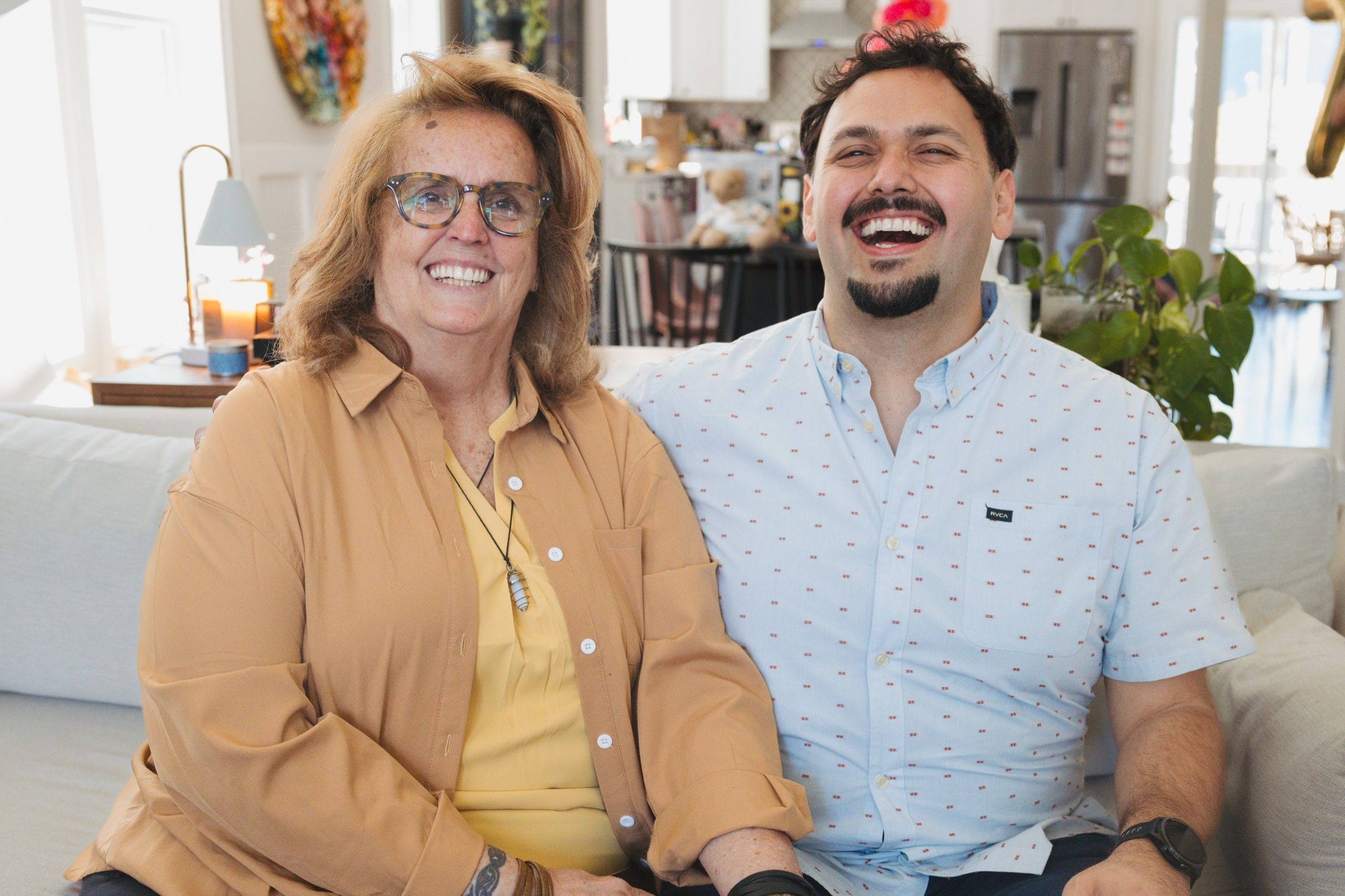 Smiling mother and adult son seated together on a couch